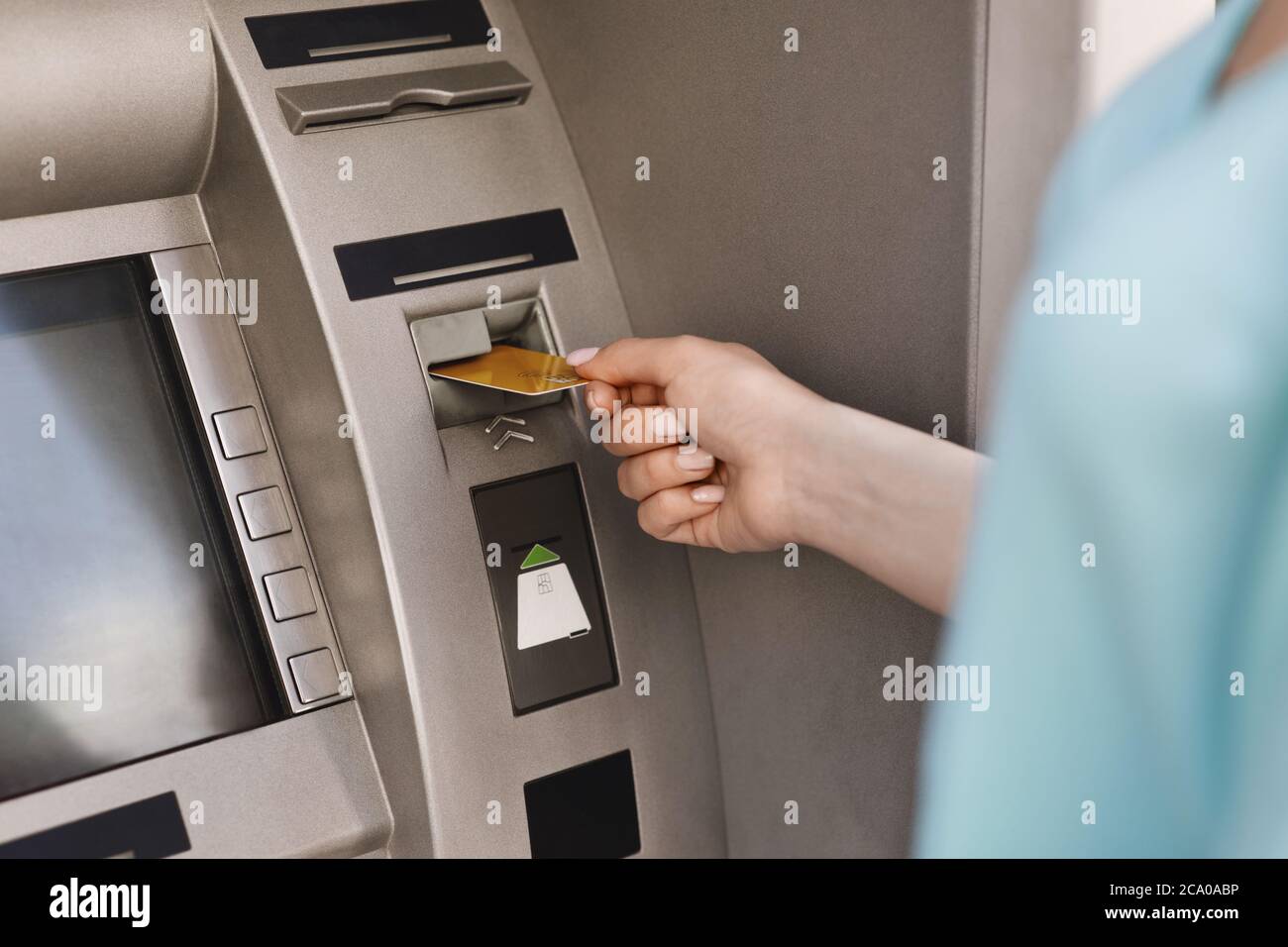 Primo piano della mano femminile che inserisce la carta di credito nella macchina ATM Foto Stock