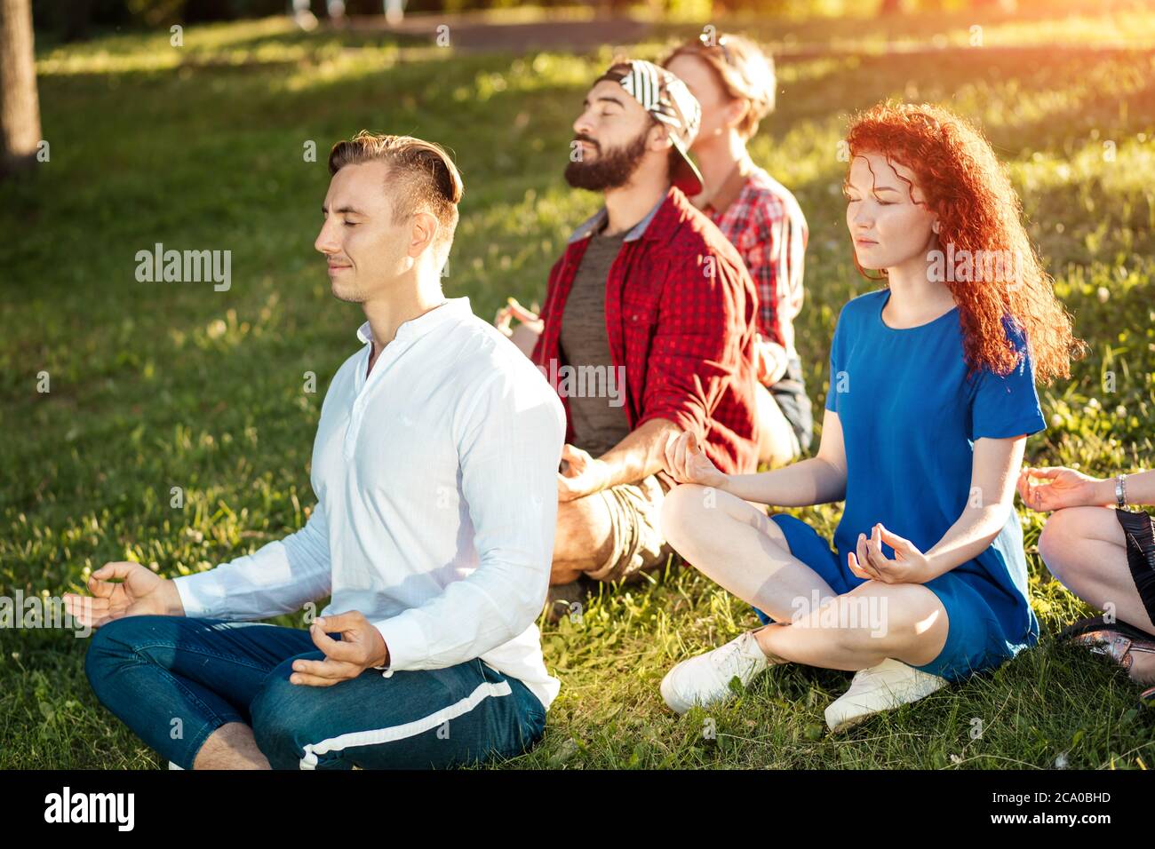 Gruppo di persone multietniche che si dialogano tra loro dopo essersi esercitate al parco. Coppie in una conversazione dopo una sessione di yoga all'aperto. Allegro gr Foto Stock