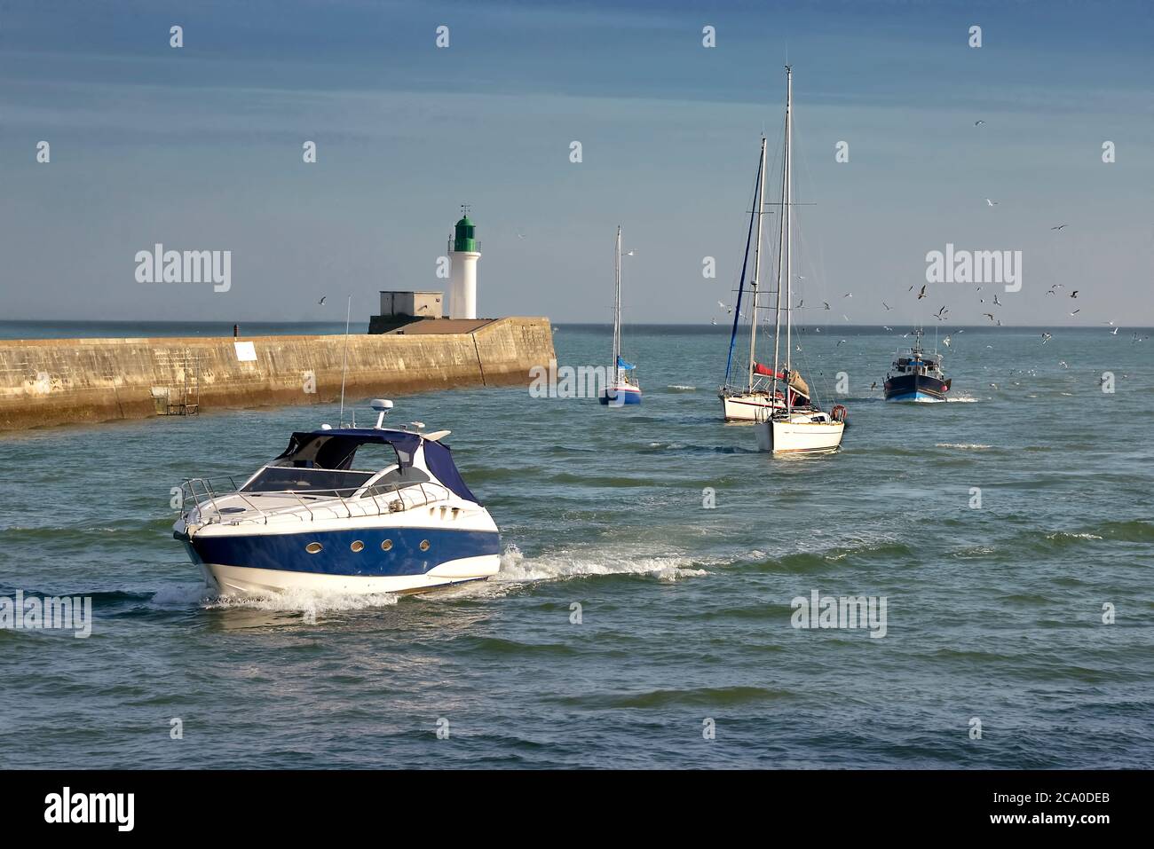 Faro e barche di ritorno al porto di Les Sables d'Olonne, comune nel dipartimento della Vandea nella regione della Loira nella Francia occidentale Foto Stock