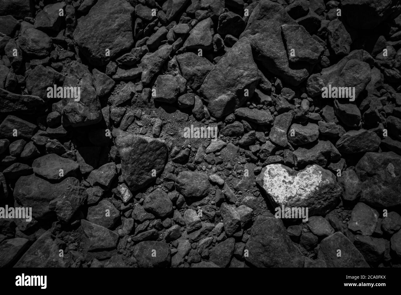 Pietra bianca a forma di cuore tra scuri rocce vulcaniche sfondo con copia spazio. Visto a Lanzarote, Isole Canarie, Spagna. Foto Stock