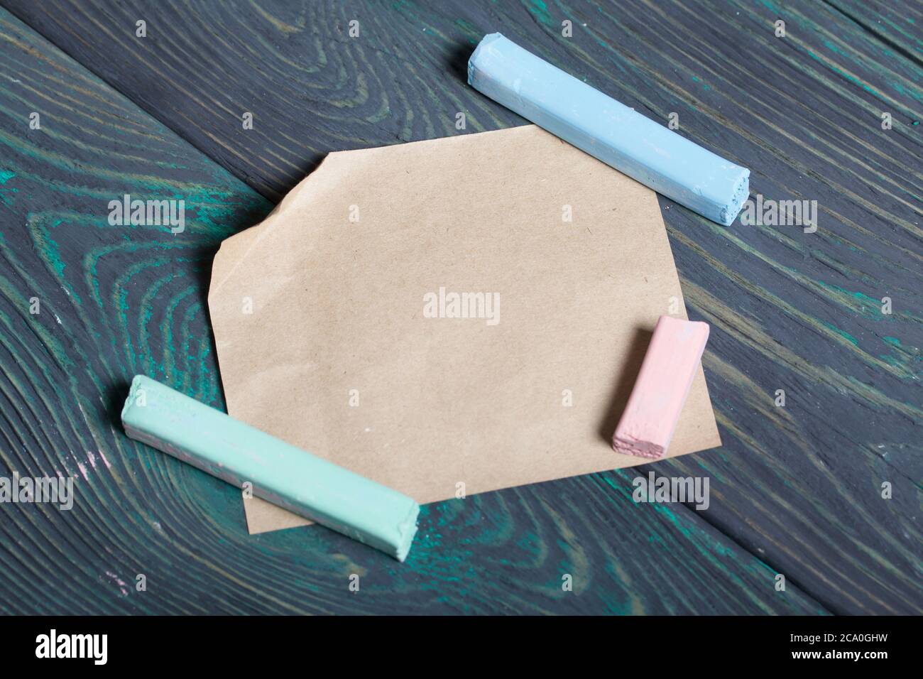 Gesso di colori diversi e un foglio di carta. Su tavole di pino nero-verde. Foto Stock