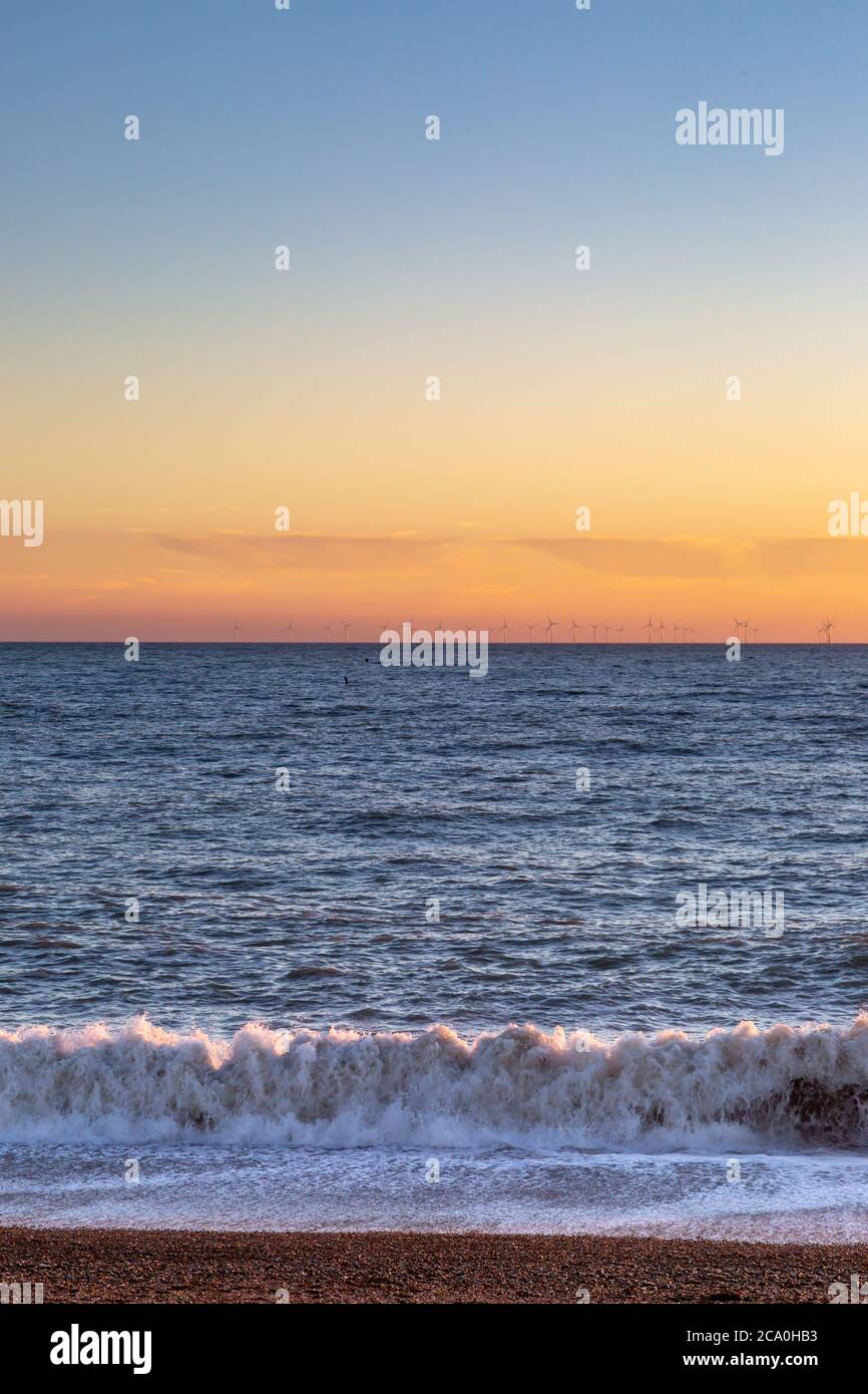 Tramonto a Brighton Beach, con un parco eolico offshore all'orizzonte Foto Stock