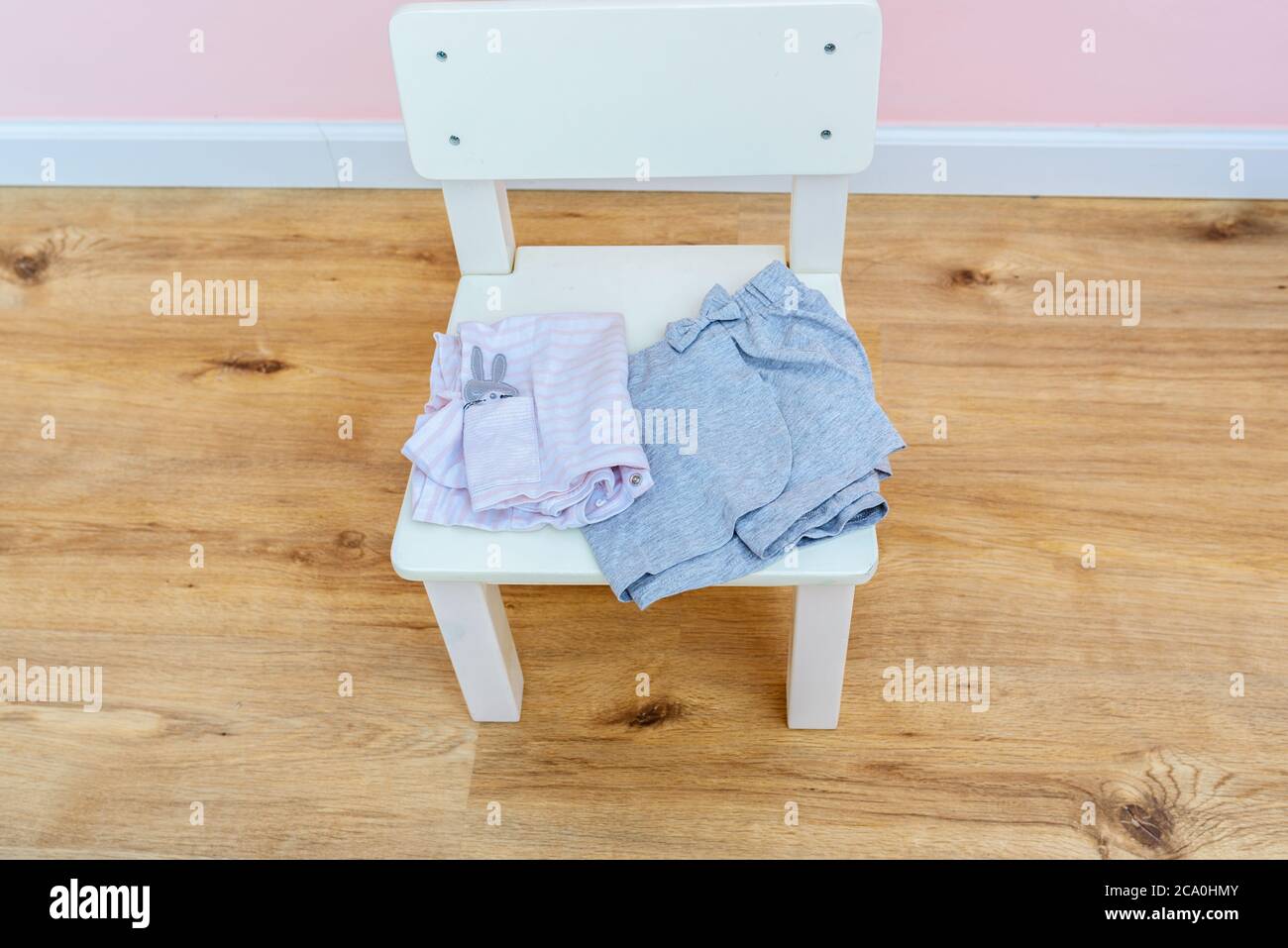 Forniture scolastiche, vestiti in camera per bambini su sedia di legno bianco. Mamma genitori che preparano l'abito per la figlia da indossare il primo giorno di prescolare. Foto Stock
