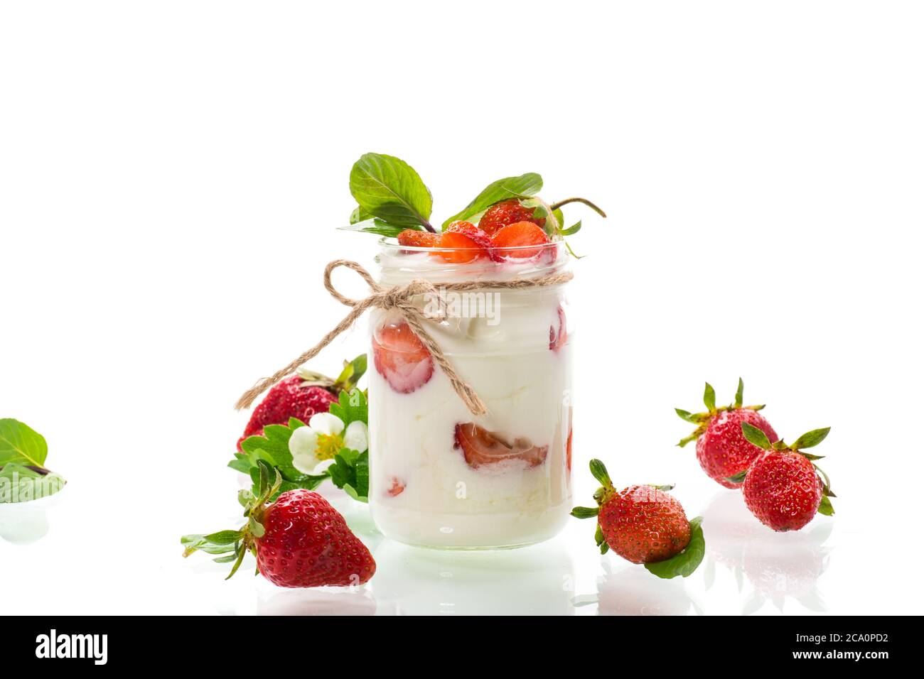 yogurt dolce fatto in casa con fragole fresche mature in un vaso isolato su sfondo bianco Foto Stock