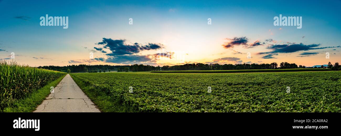 Panorama, tramonto sui campi e villaggio austriaco con cielo drammatico Foto Stock