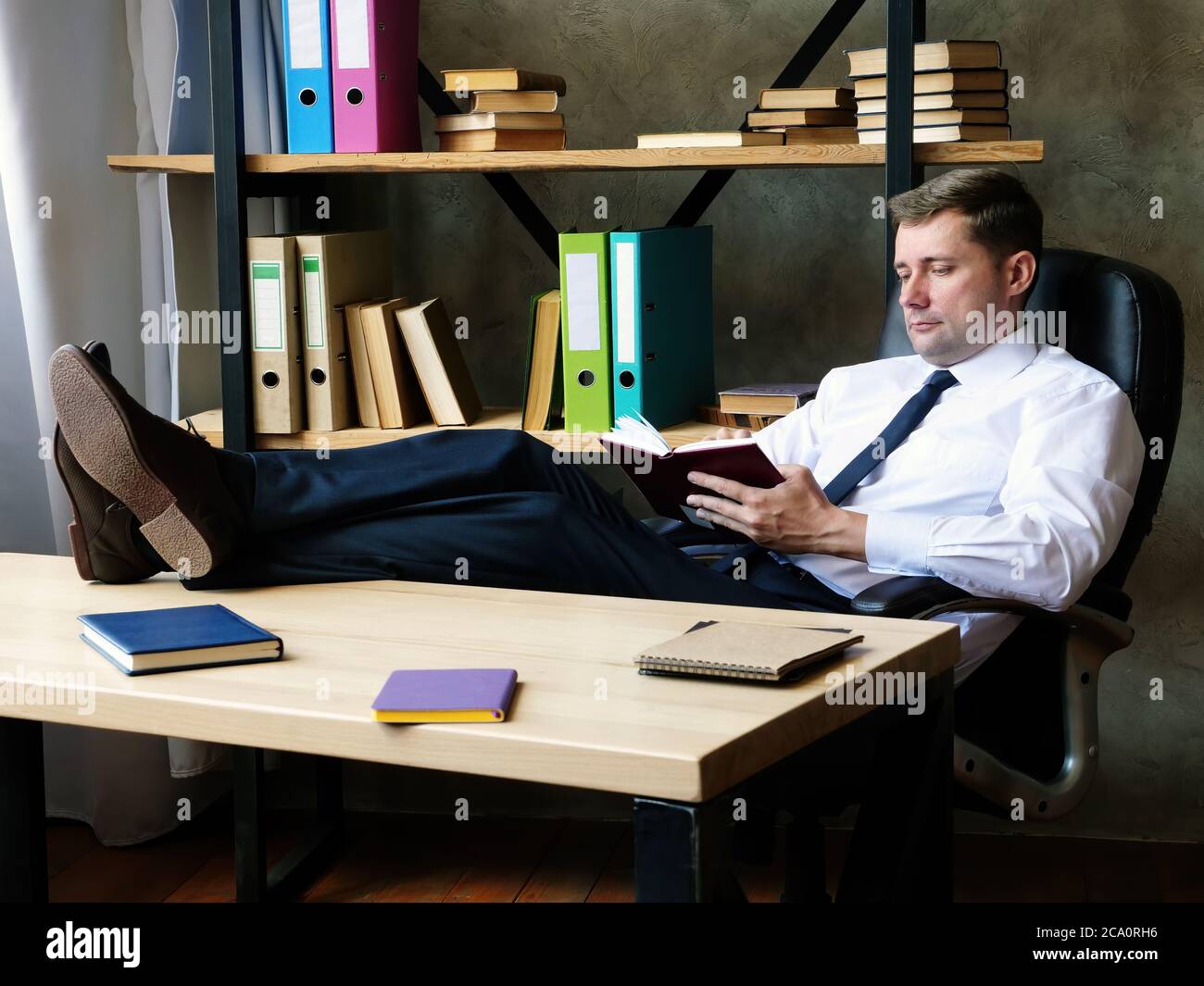 Un giovane uomo d'affari sicuro in ufficio prende appunti in un notebook. Foto Stock