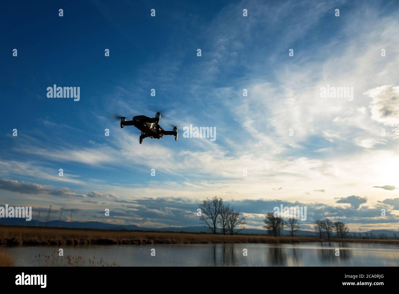 Piccolo e moderno drone di scattare una foto del lago al tramonto. Foto Stock
