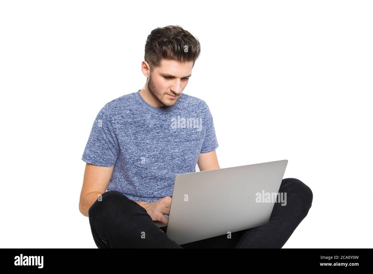 teen nerd isolato di fronte a tipi di laptop diversi pensa al suo computer, mentre si siede a terra con le gambe incrociate ed essere rivettato da qualcosa Foto Stock