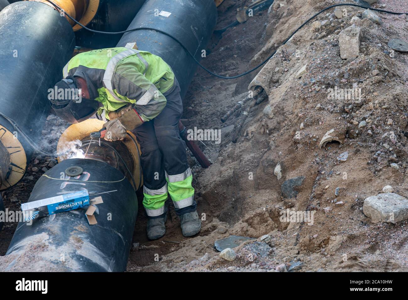 Saldatura elettrica del saldatore su tubo di teleriscaldamento isolato a Helsinki, Finlandia Foto Stock