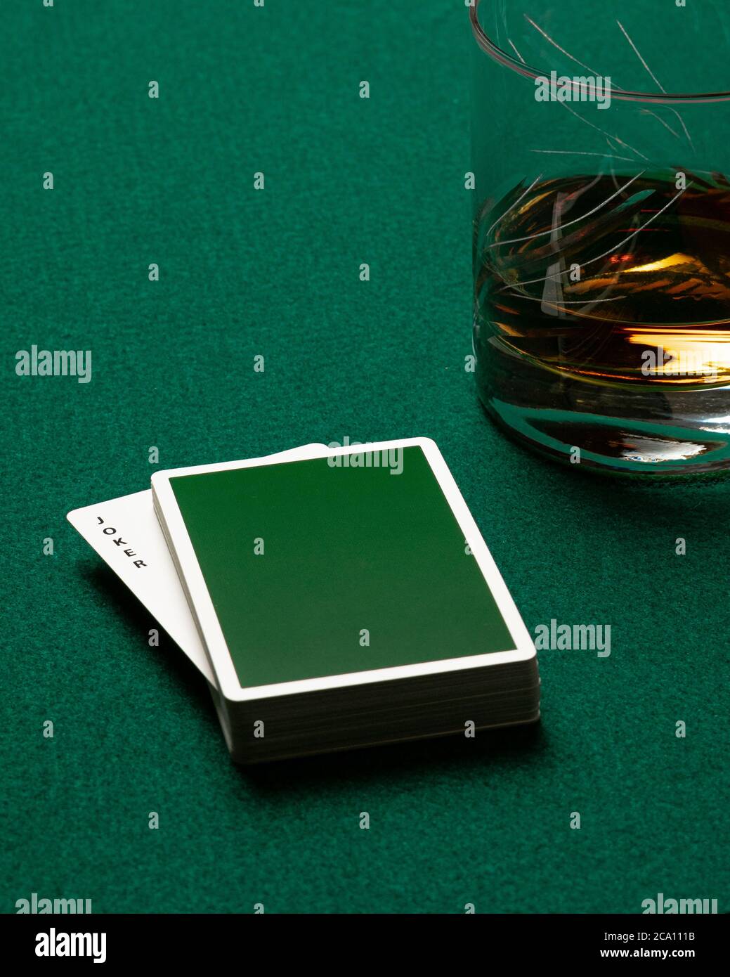 Mazzo di poker verde sulla parte superiore di un tappetino del casinò che rivela il Joker. Foto Stock