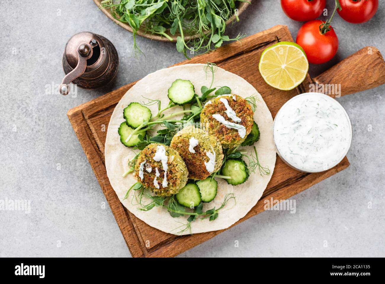 Falafel vegano con verdure e salsa tzatziki su tavola di legno, vista dall'alto. Cibo arabo Foto Stock