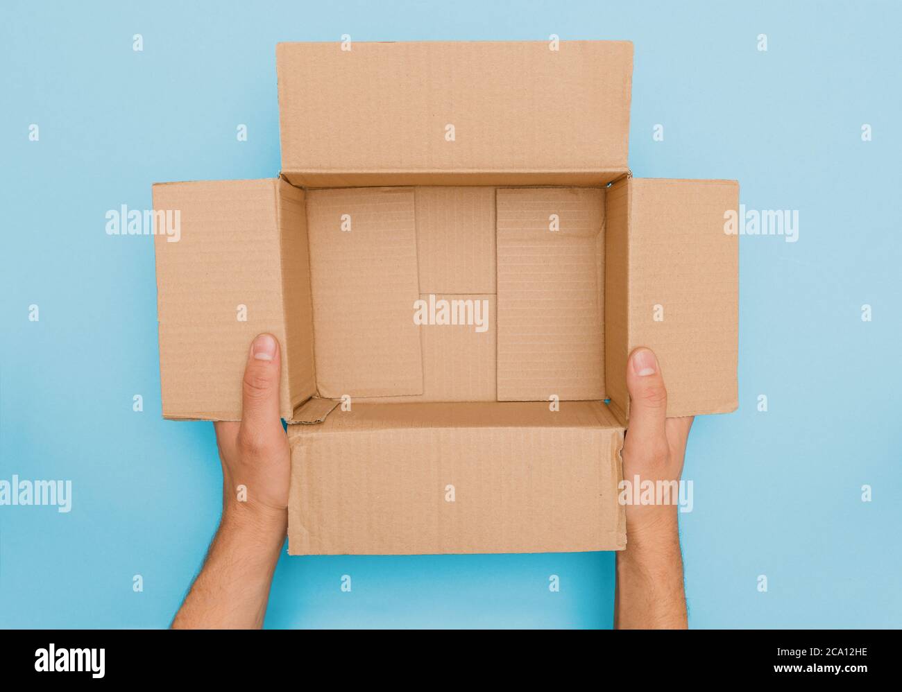 le mani maschili tengono e presentano un cartone aperto vuoto marrone confezione senza contenuto in vista dall'alto pronta per essere riempite con roba e spedizione Foto Stock