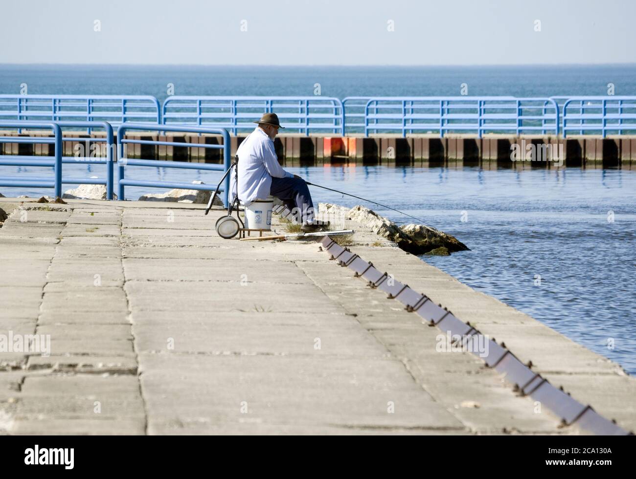 Uomo che pesca al largo di calcestruzzo breakwater sul lago Michigan a Two Rivers, Wisconsin. Foto Stock