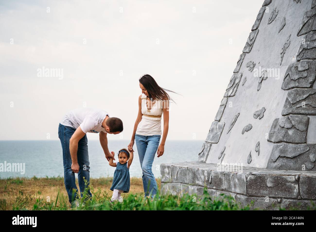 Felice giovane famiglia in magliette bianche e jeans blu con una piccola figlia in abito vicino al faro Foto stock Alamy