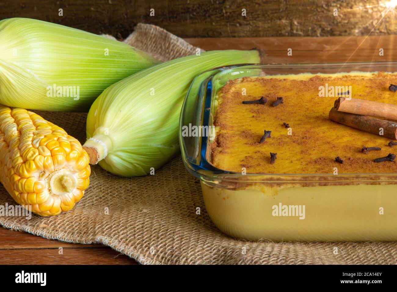 Canjica. Curau. Dolci tipici brasiliani per la festa della junina. Pannocchie di mais. Rustico legno di fondo. Dessert brasiliano Foto Stock