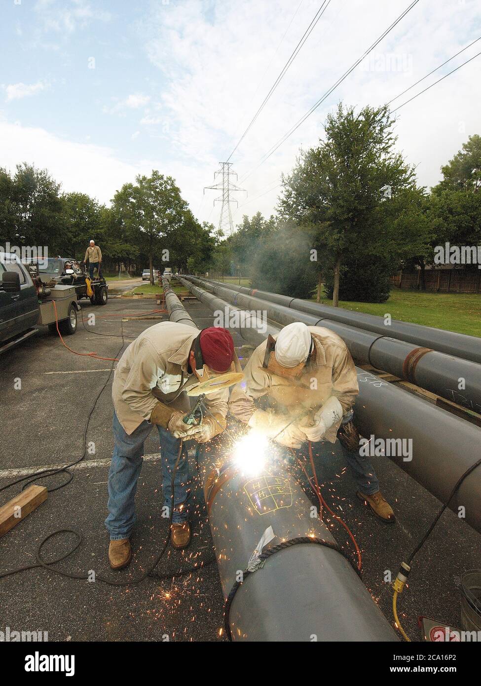 Tubi in attesa di essere aggiunti ad una conduttura che collega un sito di perforazione con una rete di condotte che portano il gas naturale alle centrali elettriche. La conduttura passa sotto linee elettriche prodotte dal gas naturale. Foto Stock