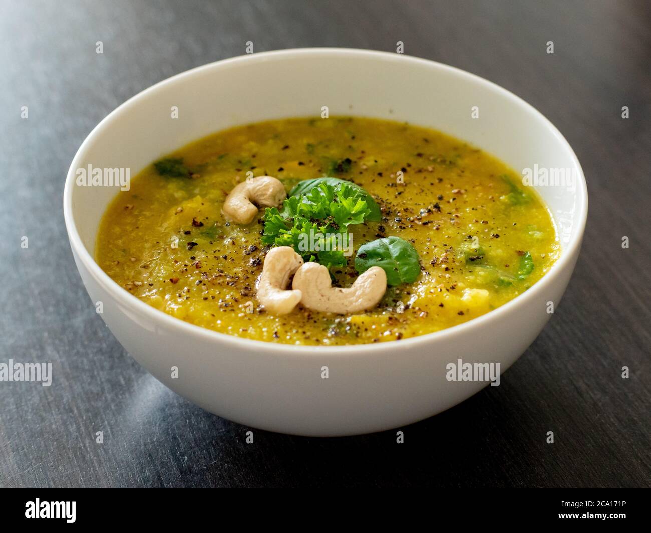 Zuppa calda di curry giallo vegano con verdure sane e verde insalata in un recipiente bianco dettaglio da vicino Foto Stock