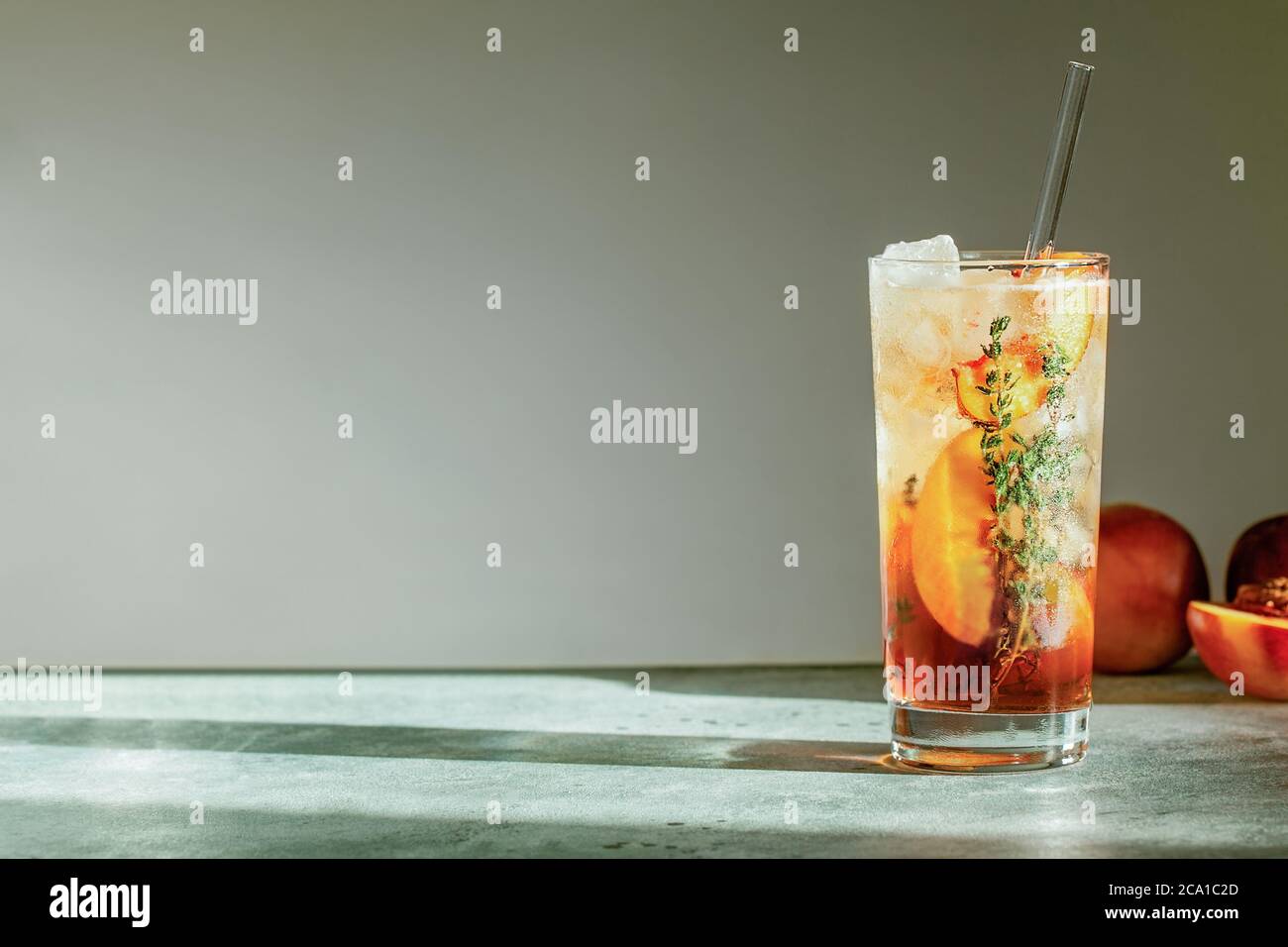 Rinfrescante tè freddo di pesca Cuba Libre o cocktail di tè freddo di Long Island in vetro con paglia. Bevanda estiva alla frutta rinfrescante. Messa a fuoco selettiva Foto Stock