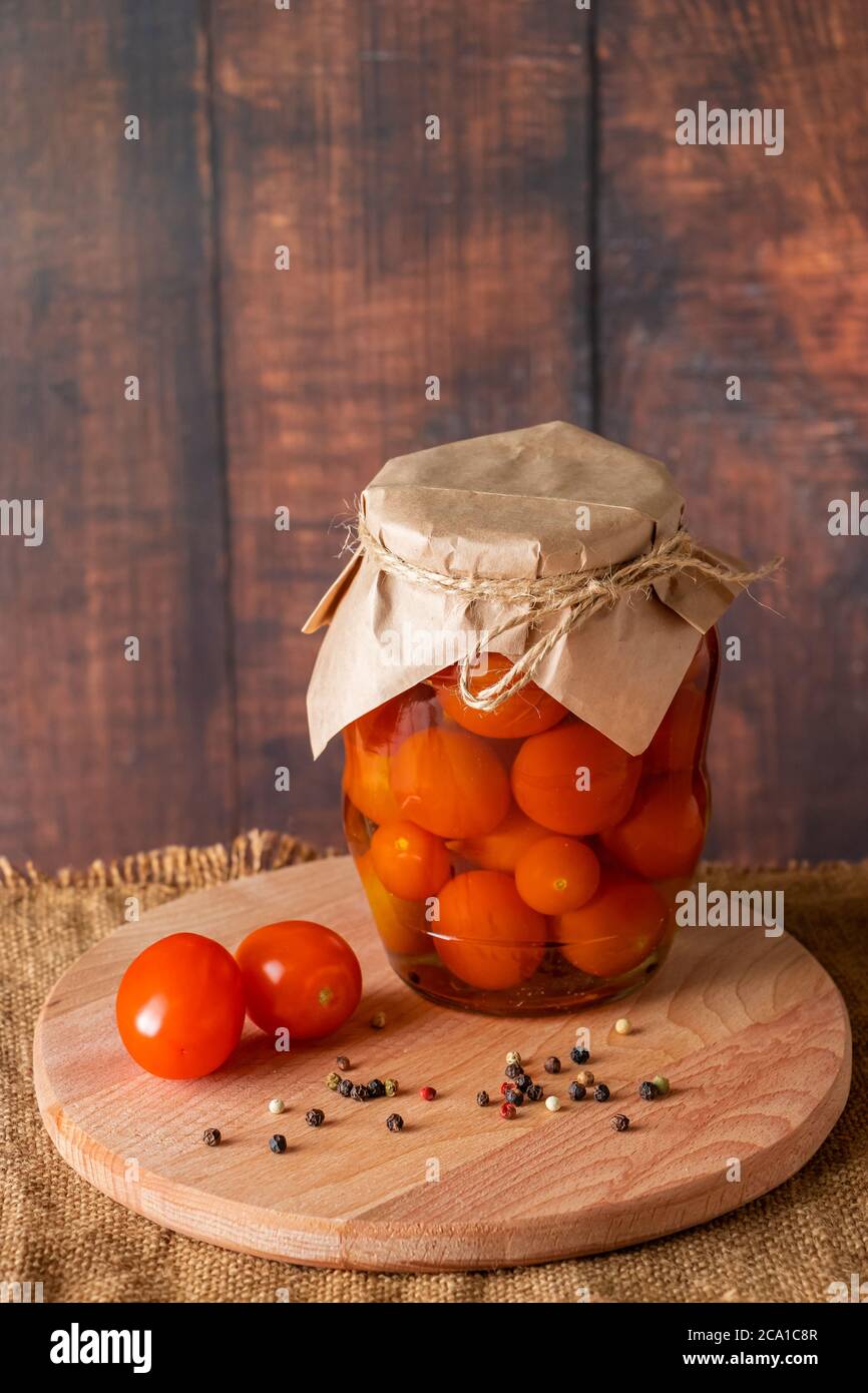 Pomodori decapati in un vaso di vetro su sfondo di legno. Cibo fermentato di tendenza. Stile rustico in casa. Foto Stock