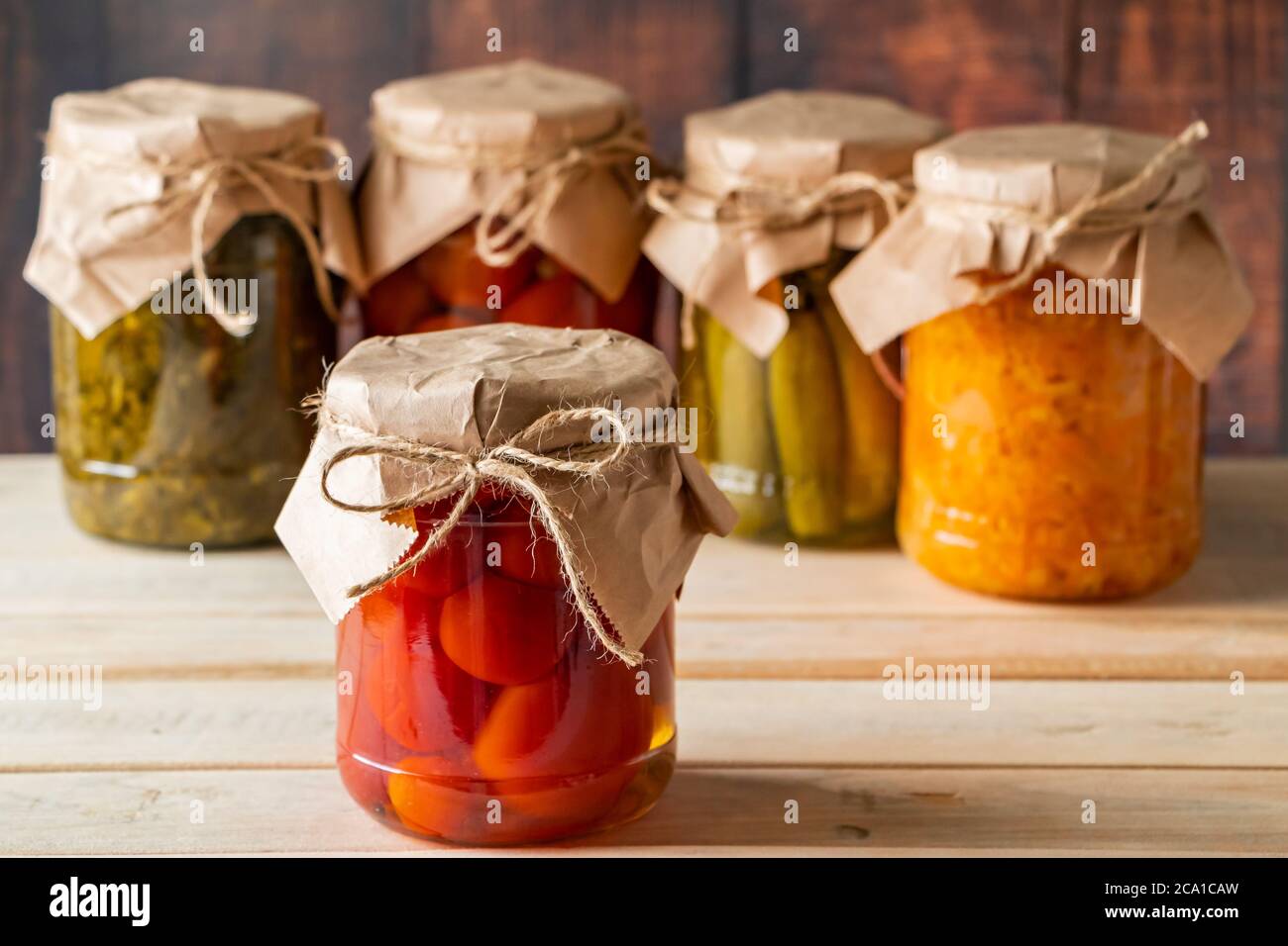 Vasetti di verdure fermentate su sfondo ligneo. Cetrioli in scatola fatti in casa, pomodori e crauti. Foto Stock