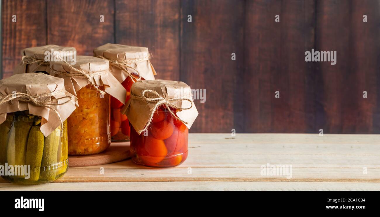 Vasetti di verdure fermentate su sfondo ligneo. Cetrioli in scatola fatti in casa, pomodori e crauti. Foto Stock