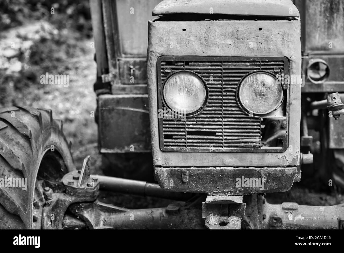 Primo piano in bianco e nero di un vecchio trattore con fari, griglia e pneumatici grandi, che mostrano dettagli rustici sulle macchine agricole. Foto Stock