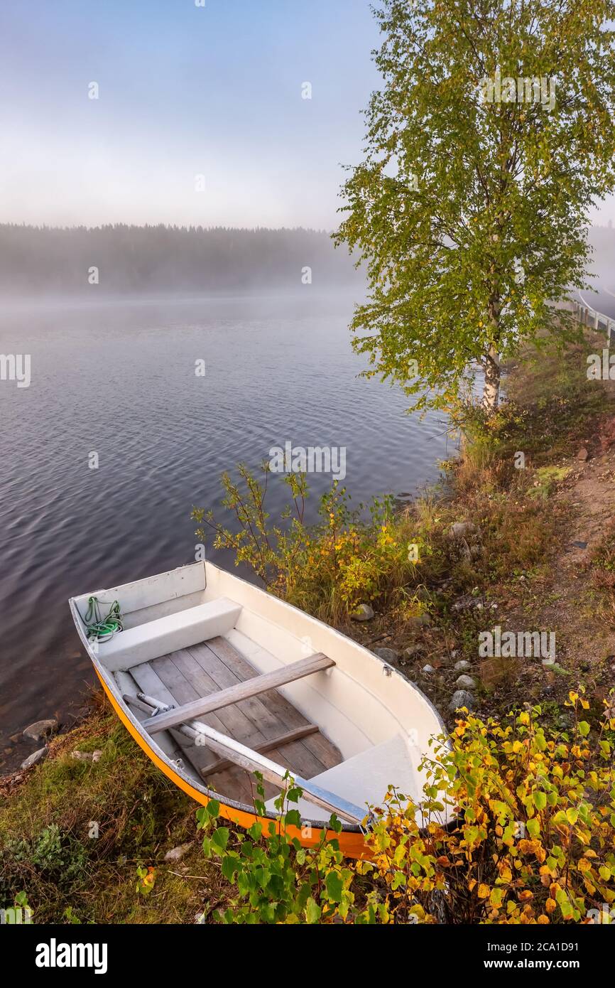 Piccola barca di legno sul lungolago in autunno in Finlandia Foto Stock