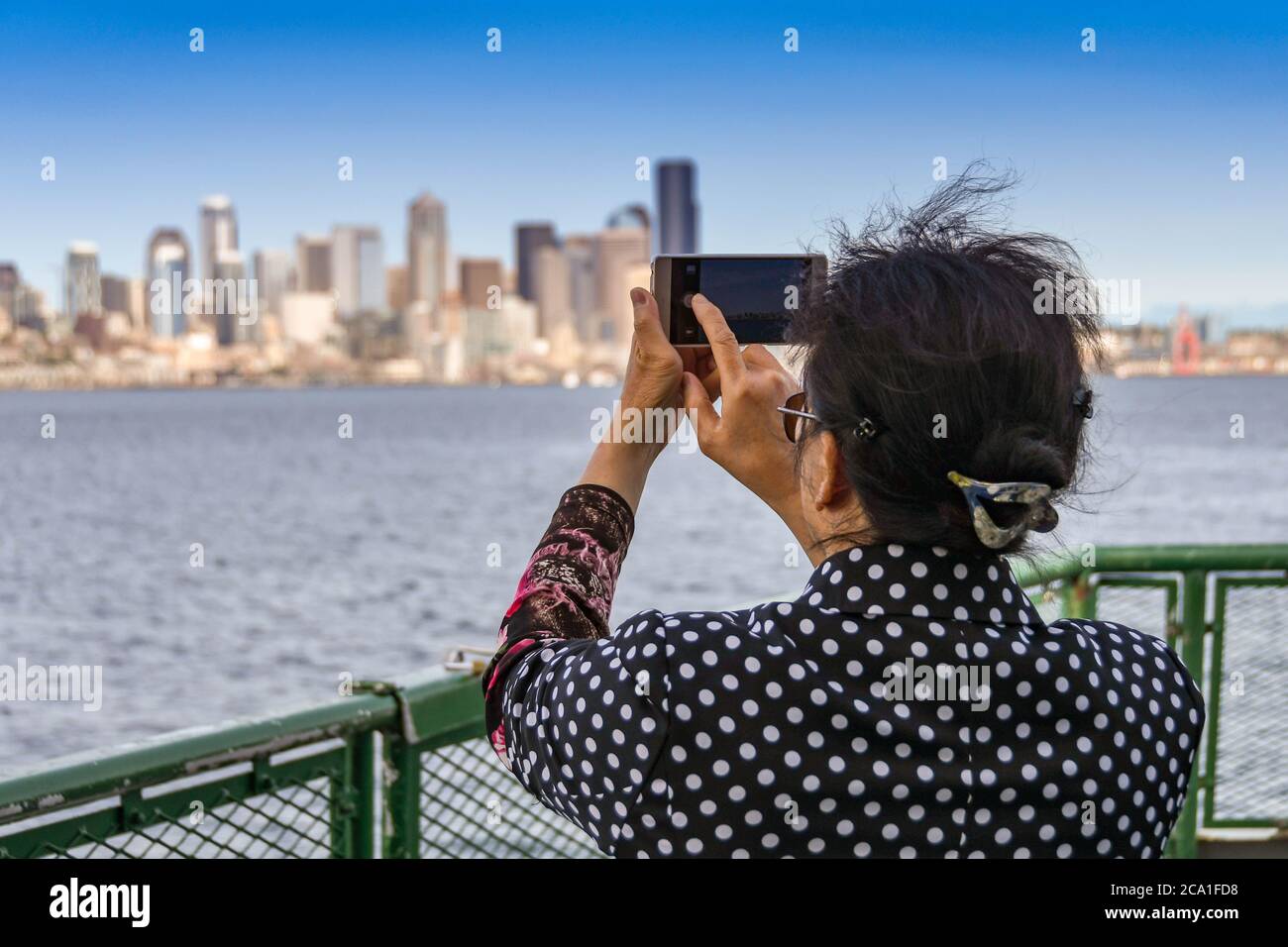 SEATTLE, STATO DI WASHINGTON, USA - GIUGNO 2018: Persona che scattano una foto dello skyline della città su un telefono con fotocamera, dal ponte di un traghetto passeggeri. Foto Stock