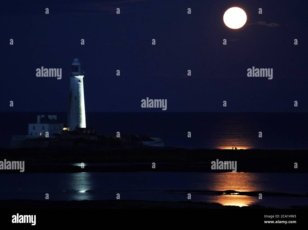 La Luna piena di Agosto, conosciuta come Sturgeon Moon, sorge sopra il faro di St Mary nella Whitley Bay. Foto Stock