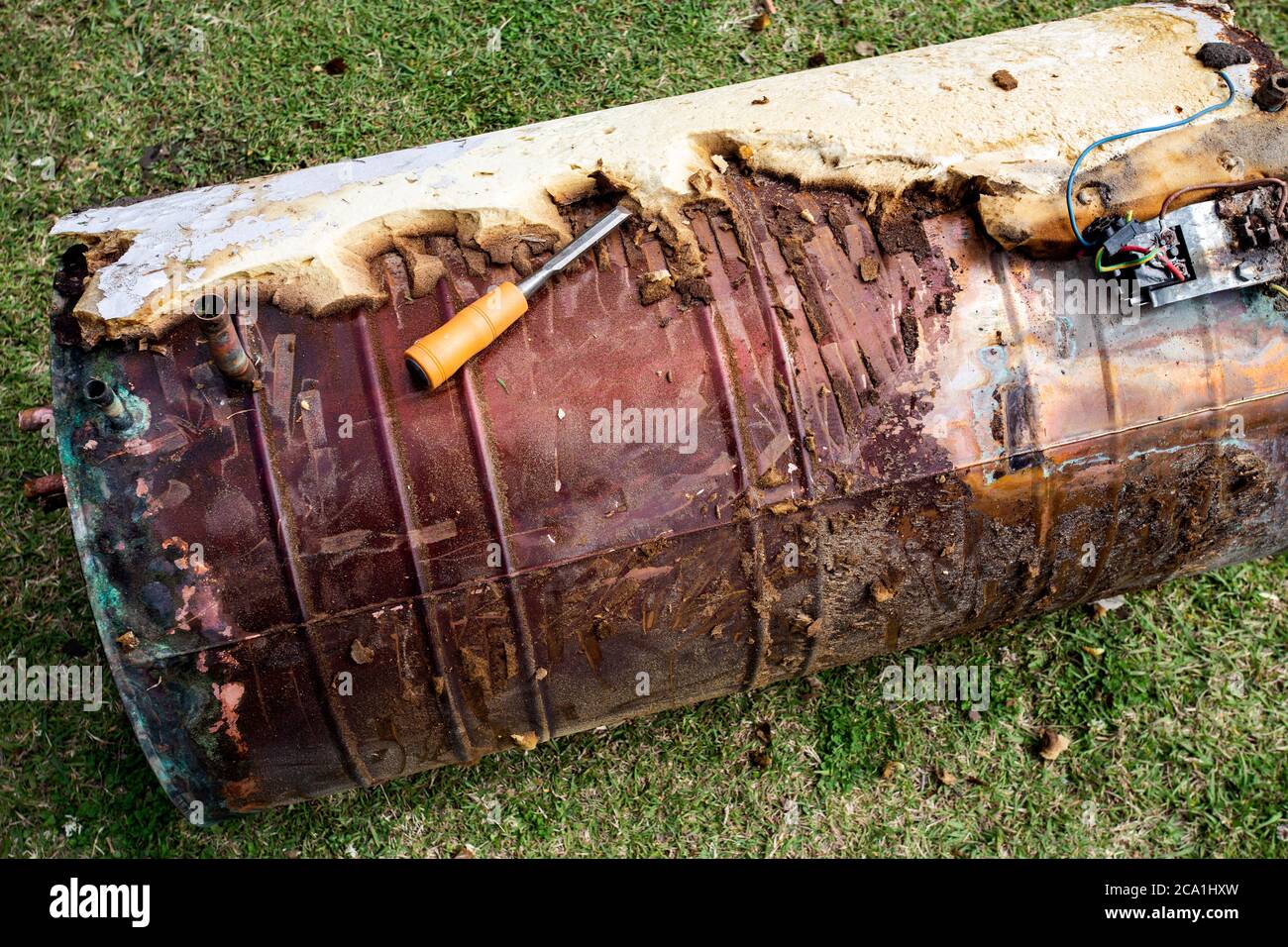 Spelatura dell'isolamento su un serbatoio di acqua calda in rame disusato per la vendita di rottami metallici Foto Stock