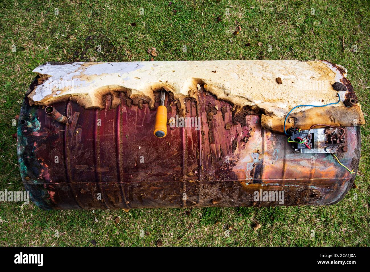 Spelatura dell'isolamento su un serbatoio di acqua calda in rame disusato per la vendita di rottami metallici Foto Stock