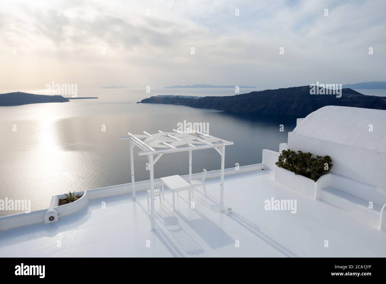 Padiglione bianco con tavolo e due sedie su una terrazza con vista panoramica sul mare. Santorini, Grecia Foto Stock