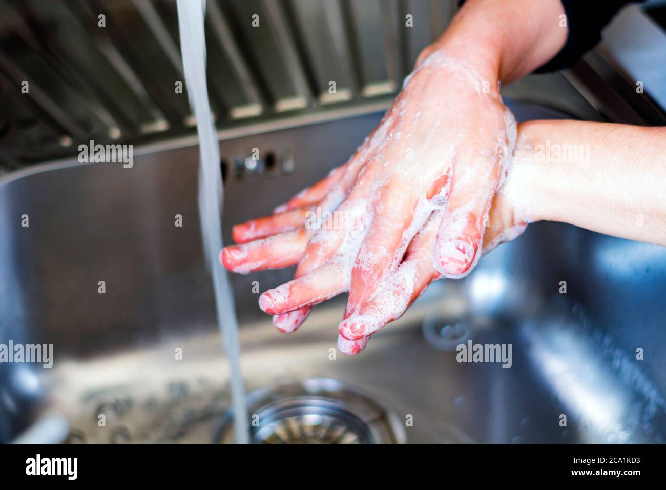 una giovane donna caucasica che le lava le mani con sapone. Coronavirus pandemia COVID-19. Mantenere pulite le mani è uno dei passaggi più importanti per evitare ge Foto Stock