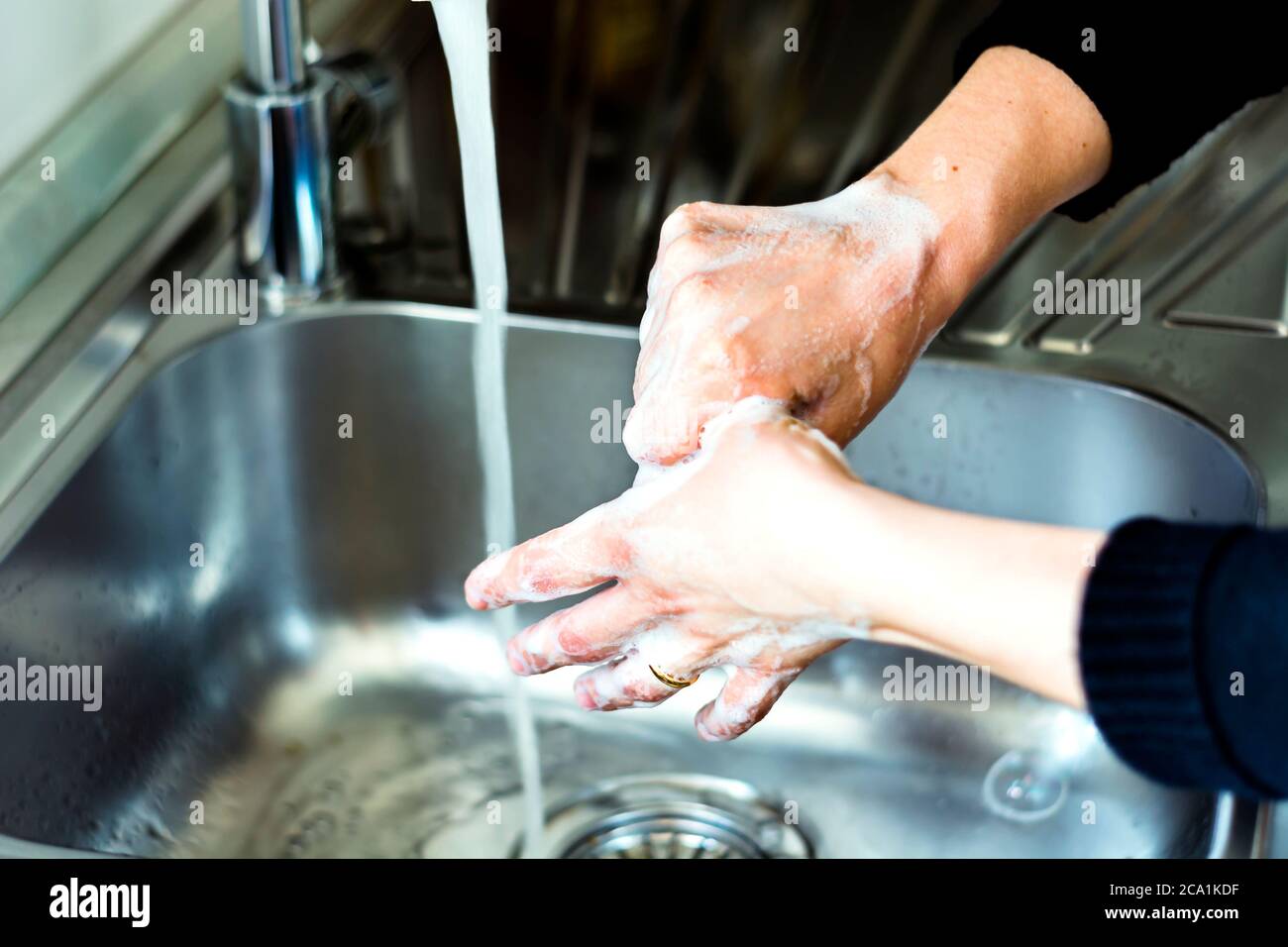 una giovane donna caucasica che le lava le mani con sapone. Coronavirus pandemia COVID-19. Tenere le mani pulite è importante evitare di ammalarsi e spreadi Foto Stock