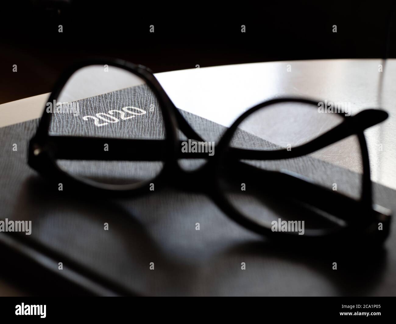 diario 2020 nero con occhiali da lettura su tavolo bianco Foto Stock