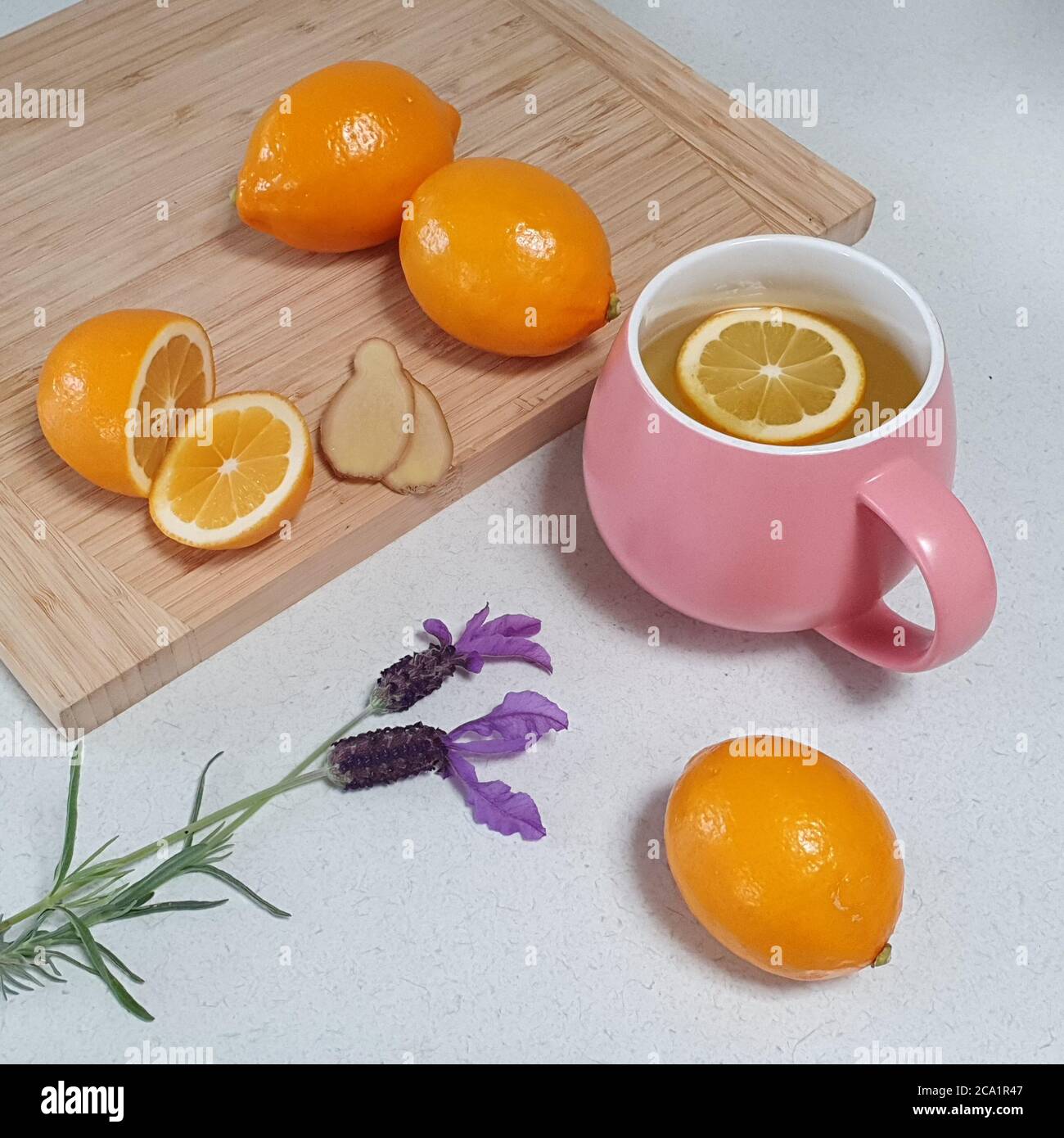 tè sano al limone caldo e zenzero in tazza rosa con limoni freschi Foto Stock