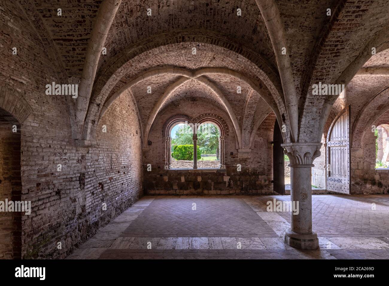 Interno della sala di un antico monastero medievale, con una volta a croce gotica e due bifore Foto Stock