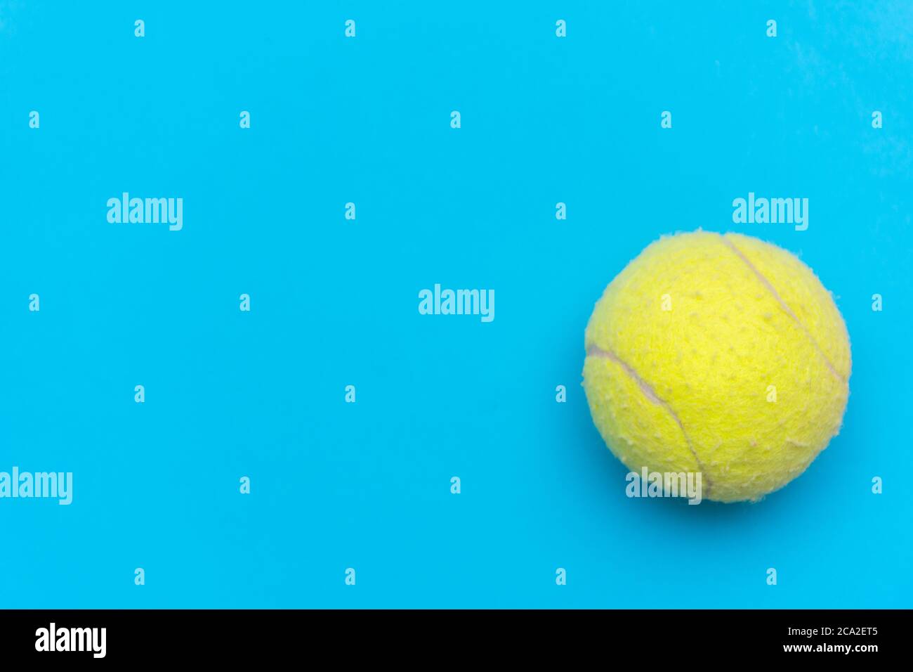 Palla da tennis giallo brillante su un solido fondo piatto blu acqua simboleggia sport e attività con spazio per le copie. Foto Stock
