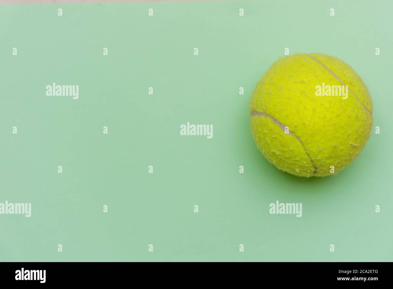 Palla da tennis giallo brillante su un solido sfondo piatto verde pastello simboleggia sport e attività con spazio copia. Foto Stock