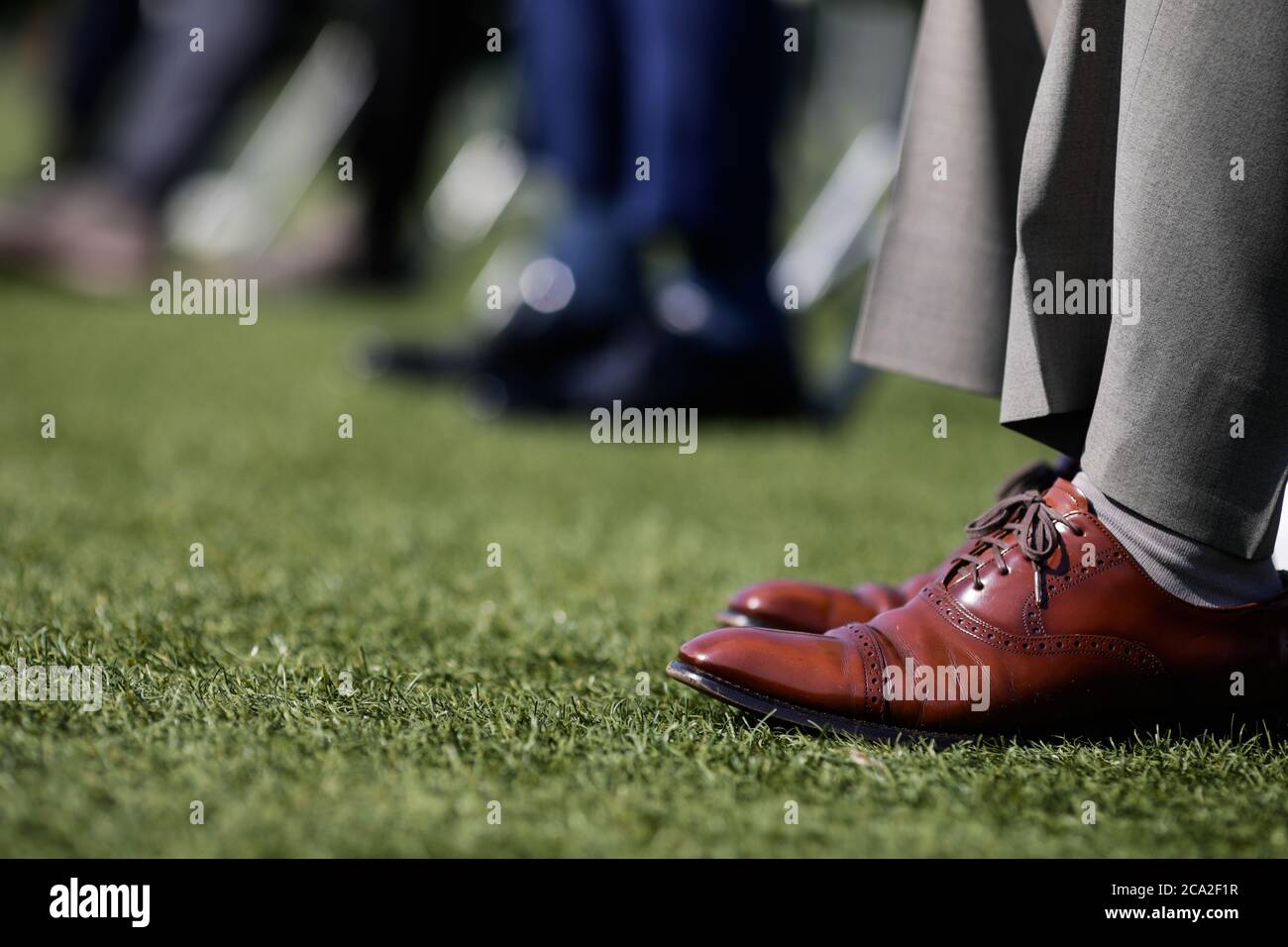 Dettagli con le scarpe di un uomo durante un evento sul tappeto erboso di uno stadio. Foto Stock