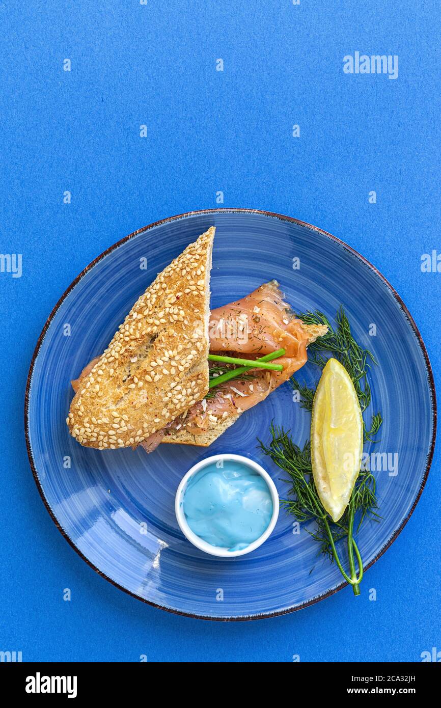 Tartine di salmone affumicato norvegese con limone, salsa di formaggio blu, pepe e sale dall'alto, su sfondi colorati. Disposizione piatta. Vista dall'alto. Foto Stock