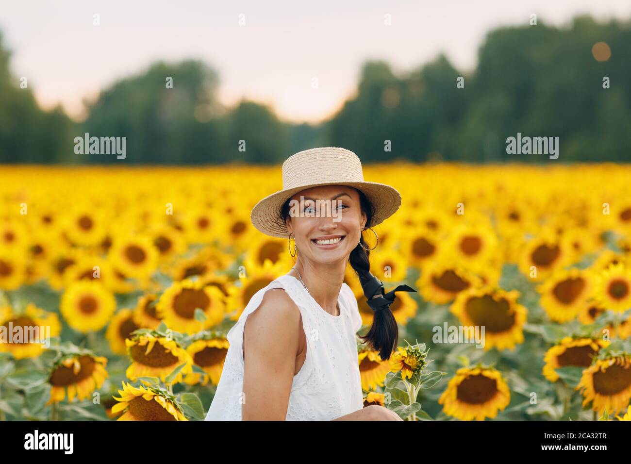 Bella giovane donna in un cappello su un campo di girasoli. Foto Stock