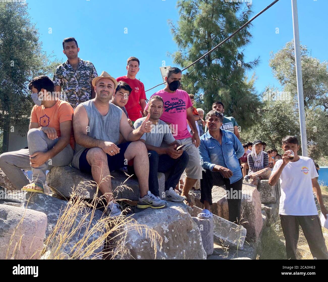 Lesbos, Grecia. 04 agosto 2020. I rifugiati afghani siedono su pietre a Camp Kara Tepe. Laschet (CDU), primo ministro della Renania Settentrionale-Vestfalia, sta visitando il campo profughi sull'isola di Lesbos come parte di una gita di diversi giorni in Grecia. Credit: Hülsmeier/dpa/Alamy Live News Foto Stock