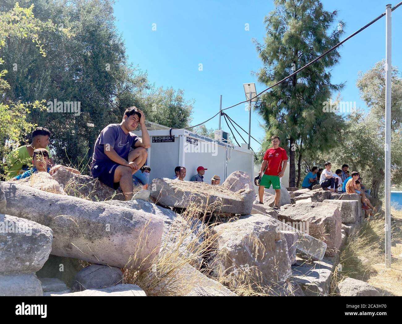 Lesbos, Grecia. 04 agosto 2020. I rifugiati afghani siedono su pietre a Camp Kara Tepe. Laschet (CDU), primo ministro della Renania Settentrionale-Vestfalia, sta visitando il campo profughi sull'isola di Lesbos come parte di una gita di diversi giorni in Grecia. Credit: Hülsmeier/dpa/Alamy Live News Foto Stock