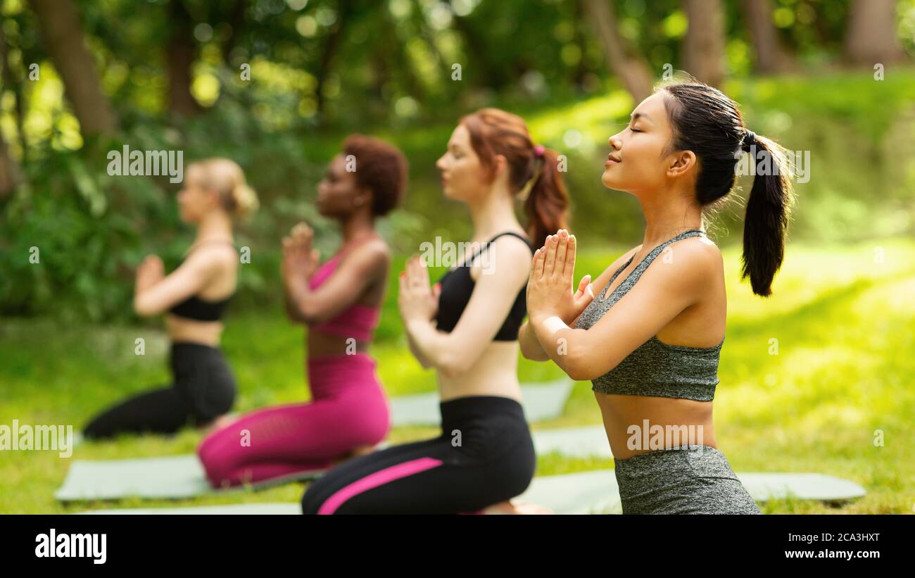 Donne multinazionali che fanno esercizi respiratori o meditazione yoga durante la pratica all'aperto, spazio libero Foto Stock
