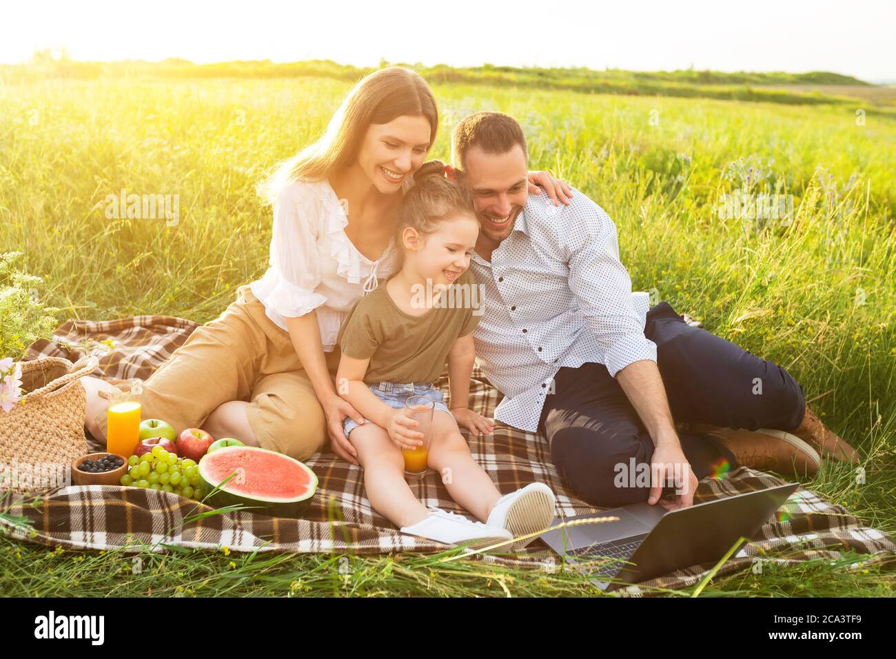 Felice famiglia insieme in un picnic con il computer Foto Stock