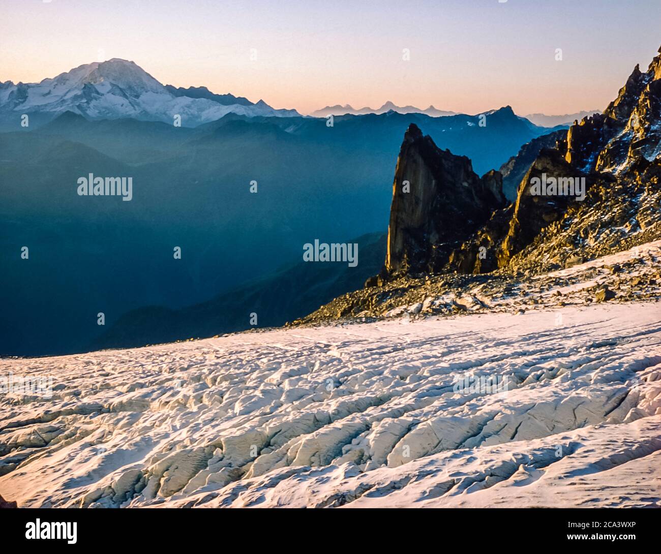 Queste sono le montagne delle Alpi Arolla in Svizzera che sono viste e attraversate sulla vecchia strada commerciale di alta montagna cacciatori tra la città francese di Chamonix e la città svizzera di Zermatt. Questa è la scena, dalla Cabane d'Orney che guarda attraverso il ghiacciaio del Tour alla lontana vetta del Grand Combin e alle ripide scogliere più vicine del Clochres du Portalet, un luogo preferito per chi volava il paracadute. Foto Stock