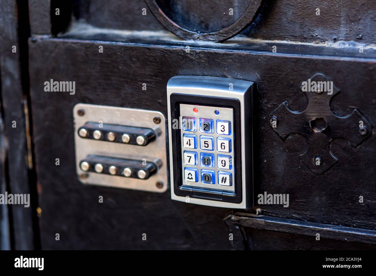 serratura a combinazione su un cancello di ferro nero con pulsanti elettronici e vecchi meccanici, primo piano. Foto Stock