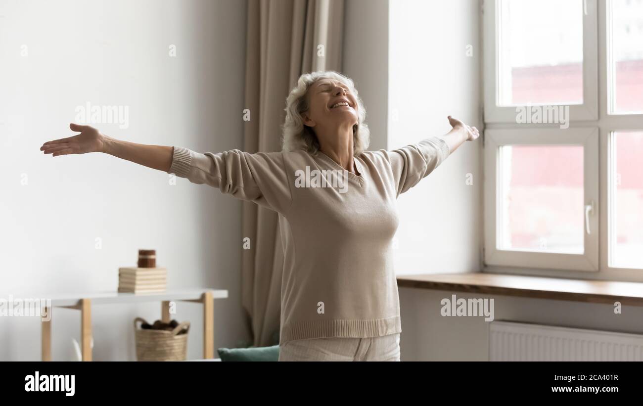 Donna anziana felice in piedi con le braccia aperte che accoglie il nuovo giorno Foto Stock