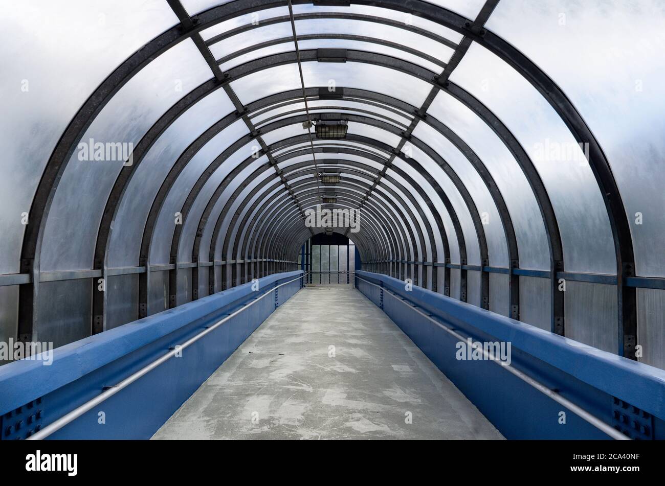 Arcade di un tunnel pedonale vuoto e sopraelevato che si restringe in lontananza Foto Stock